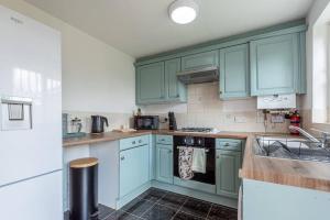 a kitchen with green cabinets and a sink at Rest & Recharge at Mapledon House (15mins to City Centre) in Manchester