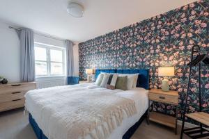 曼徹斯特的住宿－Rest & Recharge at Mapledon House (15mins to City Centre)，一间卧室配有一张带花卉壁纸的大床