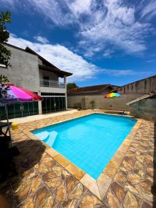 a swimming pool with a umbrella and a house at HOSTEL FAMÍLIA CASTOR in Itanhaém