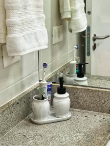 a bathroom counter with a sink with a toothbrush holder at Summer Charme in Morro de São Paulo