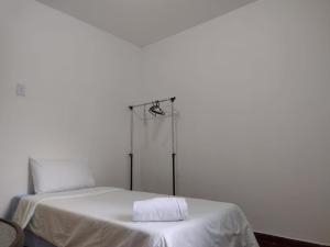 a white bed with a towel on top of it at Pousada Jardins in Macaé