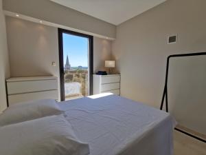 een slaapkamer met een wit bed en een raam bij MONS 4 chambres vue panoramique sur la ville et ses environs climatisation parking intra muros in Avignon