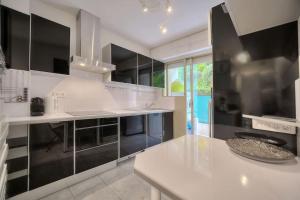 een witte keuken met zwarte kasten en een wit aanrecht bij Rocher Saint Georges spacieux 3P jardin piscine in Cannes