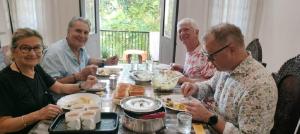 un grupo de personas sentadas alrededor de una mesa comiendo comida en Gerards Home stay Fortkochi en Kochi