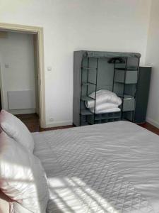 una camera da letto con un grande letto con lenzuola e cuscini bianchi di Appartement Notre Dame 2 a Montluçon