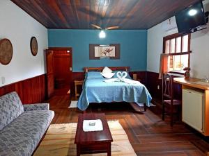 a bedroom with a bed and a couch in a room at Hotel Cantinho de Férias in Visconde De Maua