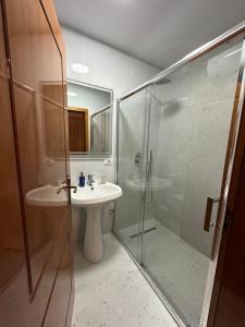 ein Bad mit einer Glasdusche und einem Waschbecken in der Unterkunft Cozy Apartment, in the center of Tirana in Tirana