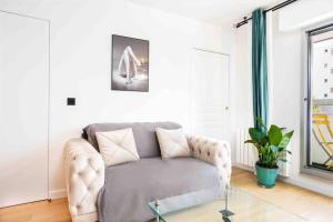 Una sala de estar con un sofá y una mesa de cristal. en Superbe appartement refait au centre de Clamart, en Clamart