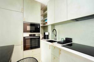 Una cocina blanca con fregadero y microondas. en Superbe appartement refait au centre de Clamart, en Clamart
