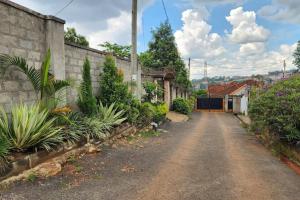 eine leere Straße mit Pflanzen an der Seite eines Gebäudes in der Unterkunft Sanz Cozy Stay; Butenga Estate, Kira. in Kira