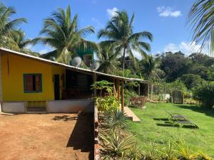 a yellow house with palm trees in the background at La Maison Cocobanana in Itacaré