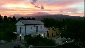 una casa con una montaña en el fondo al atardecer en Oasi Del Fiumefreddo, en Fiumefreddo di Sicilia