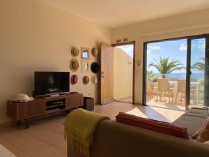 uma sala de estar com um sofá e uma televisão de ecrã plano em Casa das Pedras Pretas em Porto Santo