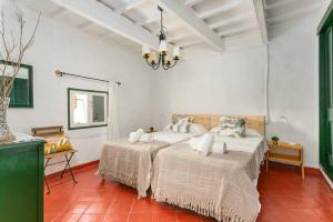 two beds in a room with white walls and red tiles at Finca BellaMirada in Es Mercadal