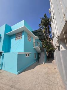 a blue building with stairs and a palm tree at SAIBALA HOMESTAY - AC 3 BHK NEAR AlRPORT in Chennai