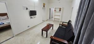 a living room with a couch and a tv at SAIBALA HOMESTAY - AC 3 BHK NEAR AlRPORT in Chennai