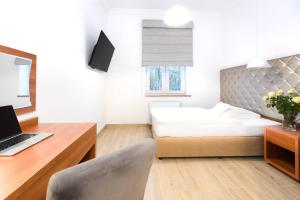 a bedroom with a bed and a desk with a laptop at Europejski Boutique Hotel in Radom