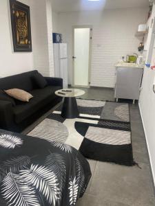 - un salon avec un canapé noir et une table dans l'établissement נופש בעמק, à Beït Shéan