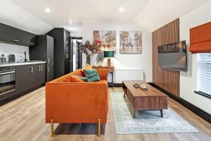 a living room with an orange couch and a table at The Eden Loft: A Stylish Retreat in Strabane
