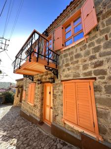 a stone house with orange doors and a balcony at Orion Adatepe in Adatepe