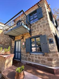 a stone house with blue shutters and a balcony at Orion Adatepe in Adatepe
