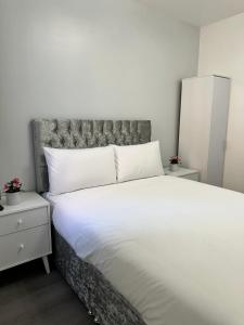 um quarto com uma grande cama branca e uma cabeceira. em Granada Apartments Holmfield Rd em Blackpool