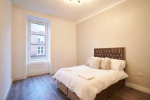 Lovely, Recently Refurbished Two Bedroom Apartment في غلاسكو: غرفة نوم بسرير ونافذة