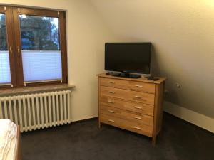 a bedroom with a tv on a dresser with a dresserngth at Meldorf-Ferienhaus in Meldorf