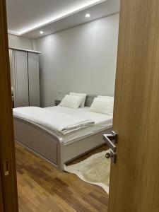una camera con letto e lenzuola bianche di Dry Lake Apartment a Tirana