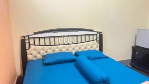 1 dormitorio con cama azul y almohadas azules en OYO 93416 Wisma Alam Syariah en Mamuju