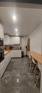 eine Küche mit einem Holztisch und weißen Schränken in der Unterkunft Maison individuelle avec jardin in Vaujours