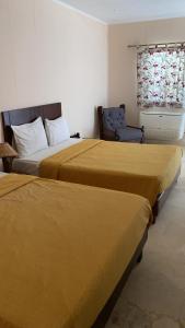 a hotel room with two beds and a chair at Sayadeen Village - Red Sea Riviera in Nuweiba