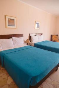 two beds in a hotel room with blue sheets at Sayadeen Village - Red Sea Riviera in Nuweiba
