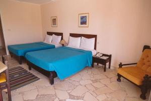 2 camas con sábanas azules en una habitación con silla en Sayadeen Village - Red Sea Riviera, en Nuweiba