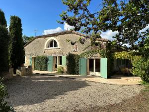 een oud stenen huis met groene deuren en een oprit bij Maison Lafuge - Piscine au cœur des vignes in Doulezon