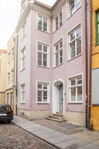 a pink house on a street with a car parked in front at Ferienwohnungen in der Altstadt Stralsund in Stralsund