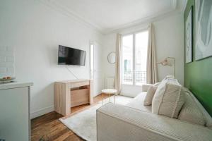 ein weißes Wohnzimmer mit einem Sofa und einem TV in der Unterkunft Apartment proche Vaugirard - Sauge - III in Paris