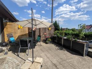 un patio con mesa y sombrilla en Urlaubsmagie - Maisonette-Wohnung mit Pool - W3, en Lichtenhain
