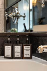 three bottles on a bathroom counter in front of a sink at Hôtel Le Germain Québec in Quebec City