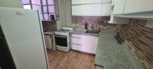 cocina pequeña con armarios blancos y fogones en Departamento 4 ambientes, 3 hab en Buenos Aires