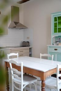 una cucina con tavolo in legno e sedie bianche di De Koetsier a Lanaken