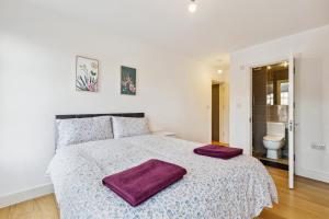 Un dormitorio blanco con una cama grande con toallas moradas. en Cozy Central London Residence Stockwell en Londres