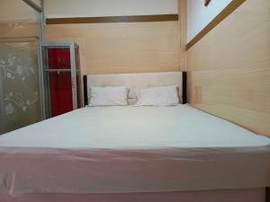 uma grande cama branca num quarto com uma porta vermelha em OYO 93278 Wisma Syariah Lahundape em Kendari