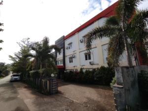 a white building with palm trees in front of it at OYO 93278 Wisma Syariah Lahundape in Kendari