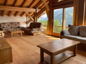 a living room with couches and a table and windows at Chalet des Laix in La Rosière