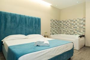 Schlafzimmer mit einem Bett mit blauem Kopfteil und einer Badewanne in der Unterkunft DEA SUITE in Giugliano in Campania