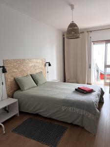 um quarto com uma cama grande e uma luz pendente em Casa Costa em Costa da Caparica