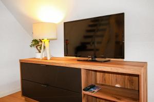 telewizor z płaskim ekranem siedzący na szczycie drewnianego centrum rozrywki w obiekcie Allgäu Residenz Natur & Spa GmbH w mieście Wiggensbach