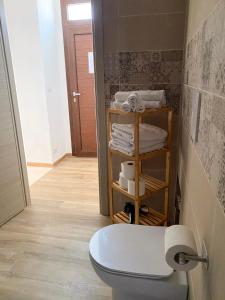 a bathroom with a toilet and a shelf with towels at B&B Lichitu in Sedilo