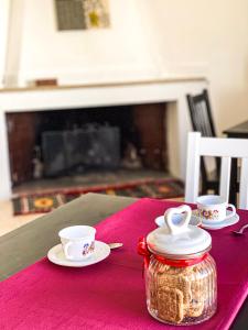 a table with two cups and a jar on a pink table cloth at B&B Lichitu in Sedilo +39 photos